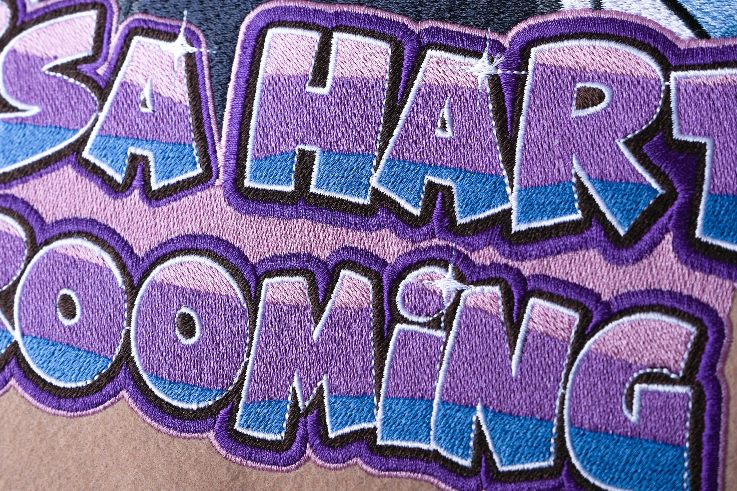 Large embroidered graffiti-style text close-up showing satin and fill stitch detail